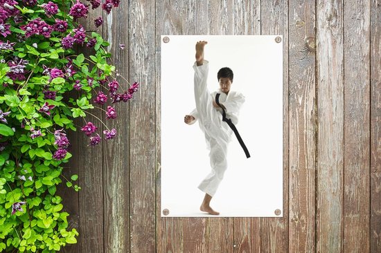 Tuinposter - Een Aziatische man die zijn been omhoog schopt bij karate - 40x60 cm