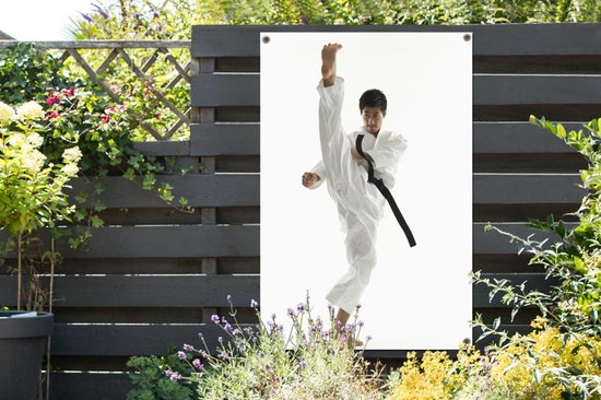 Tuinposter - Een Aziatische man die zijn been omhoog schopt bij karate - 120x180 cm - XXL