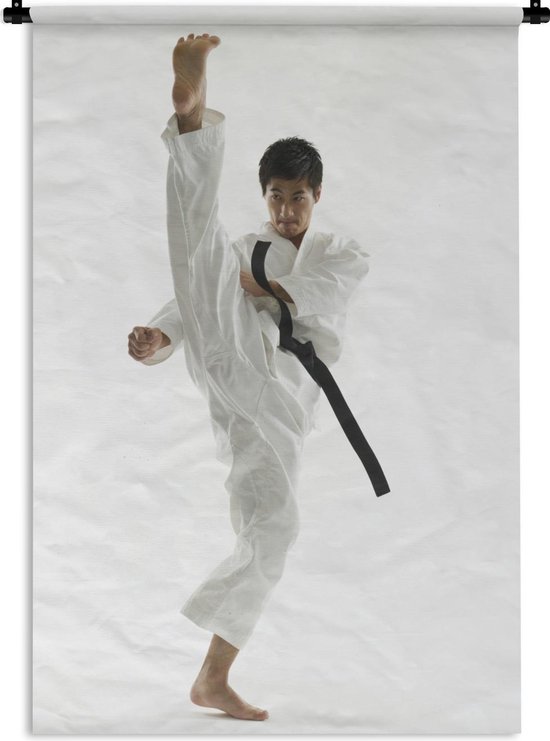 Wandkleed Karate - Een Aziatische man die zijn been omhoog schopt bij karate Wandkleed katoen 60x90 cm - Wandtapijt met foto